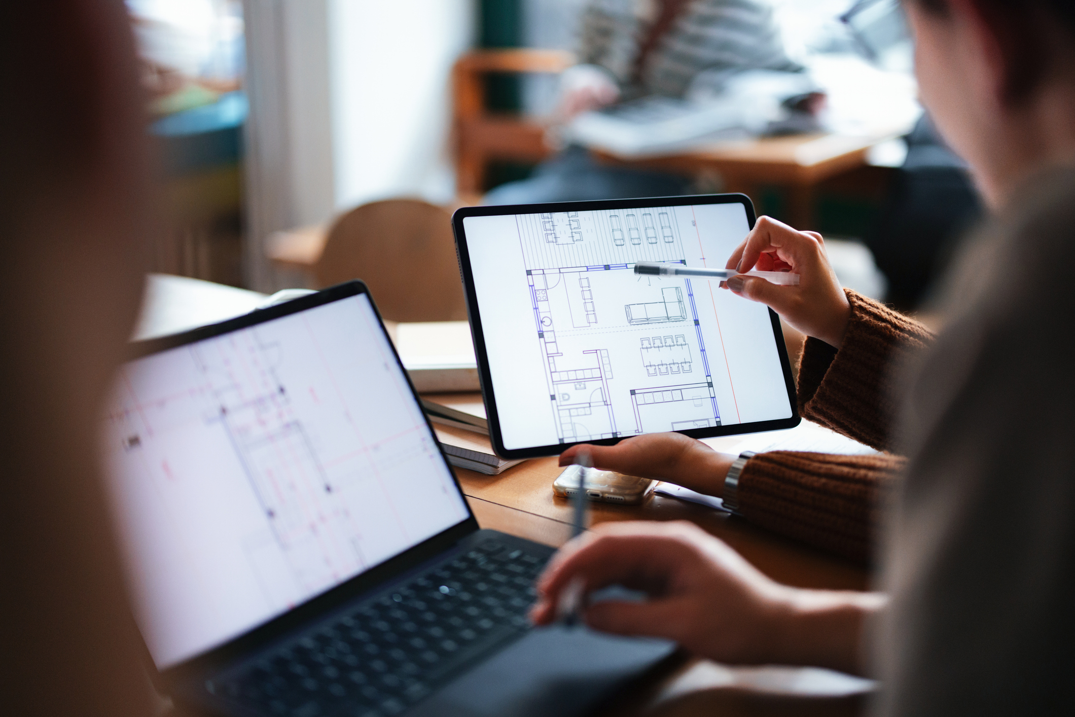 Collaborative architectural design session showcasing 3D kitchen planning on tablet and laptop, emphasizing modern tools and teamwork.