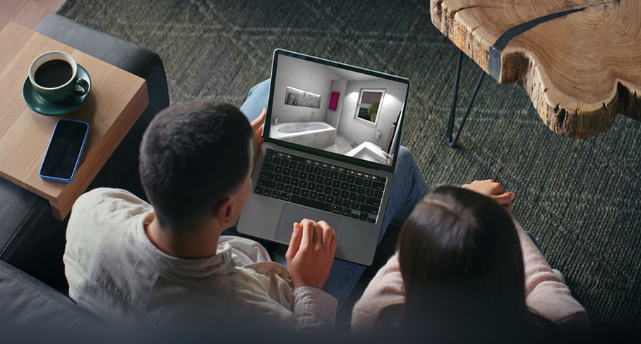 A couple is looking at the bathroom on the laptop.