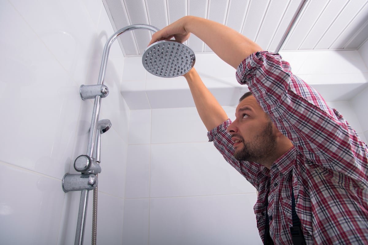 The man is fixing the shower head