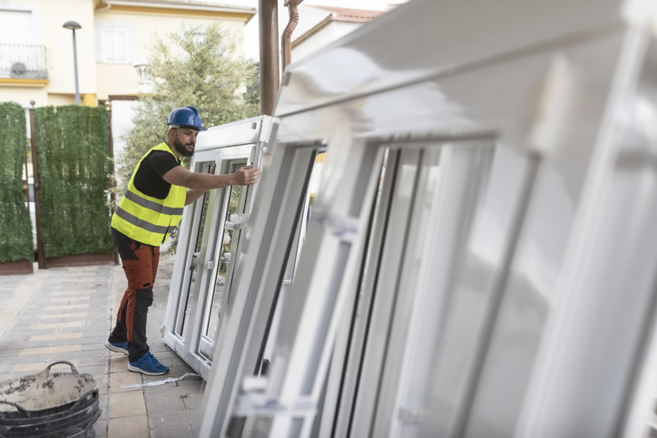 A man is working on installing a window at a construction site.
