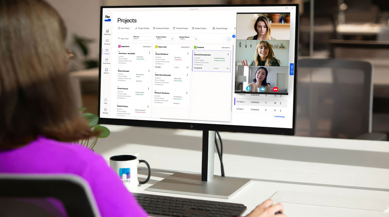 A woman at a desk participating in a video conference on her computer screen